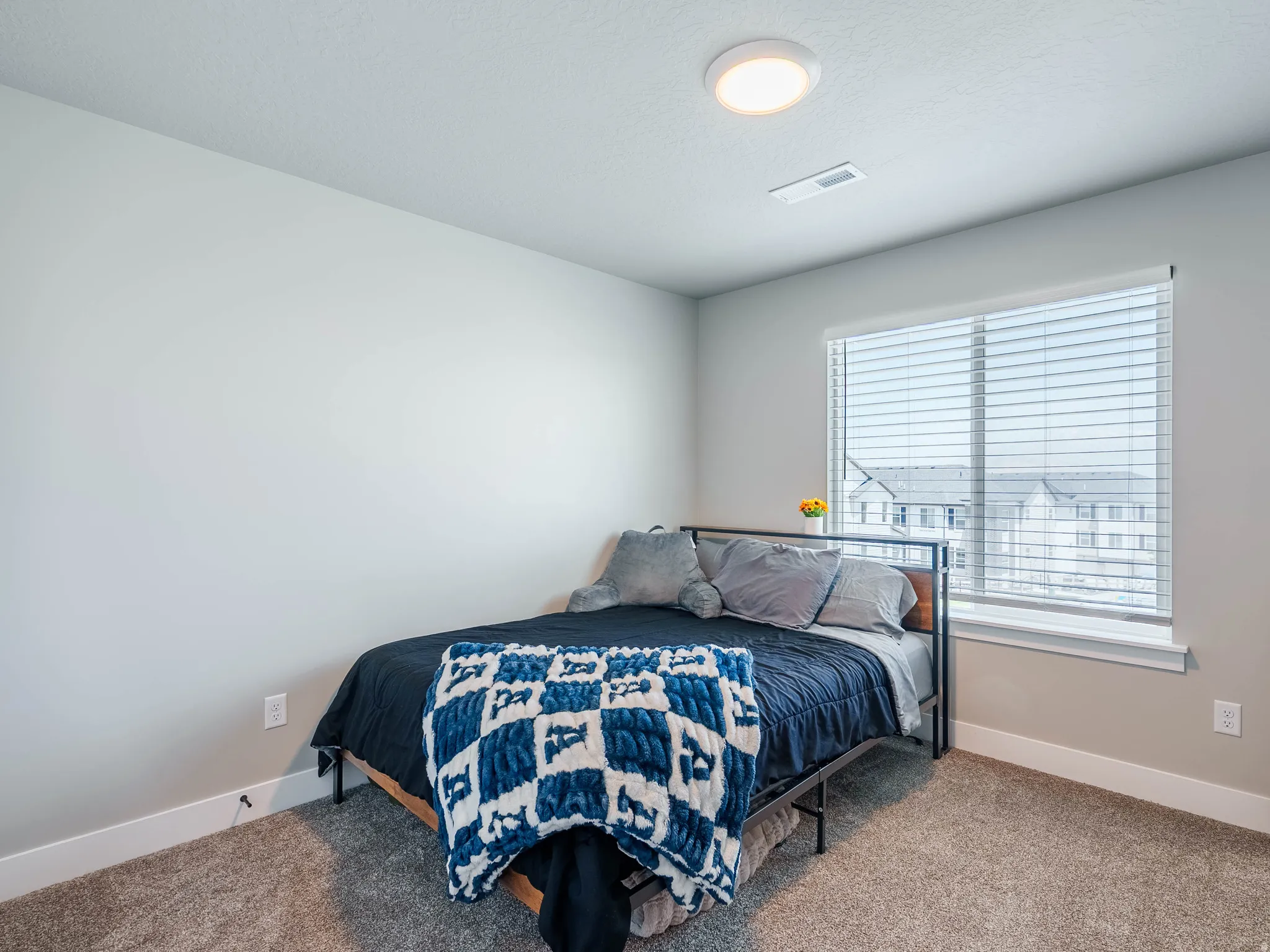 Carpeted room with a large window featuring horizontal blinds
