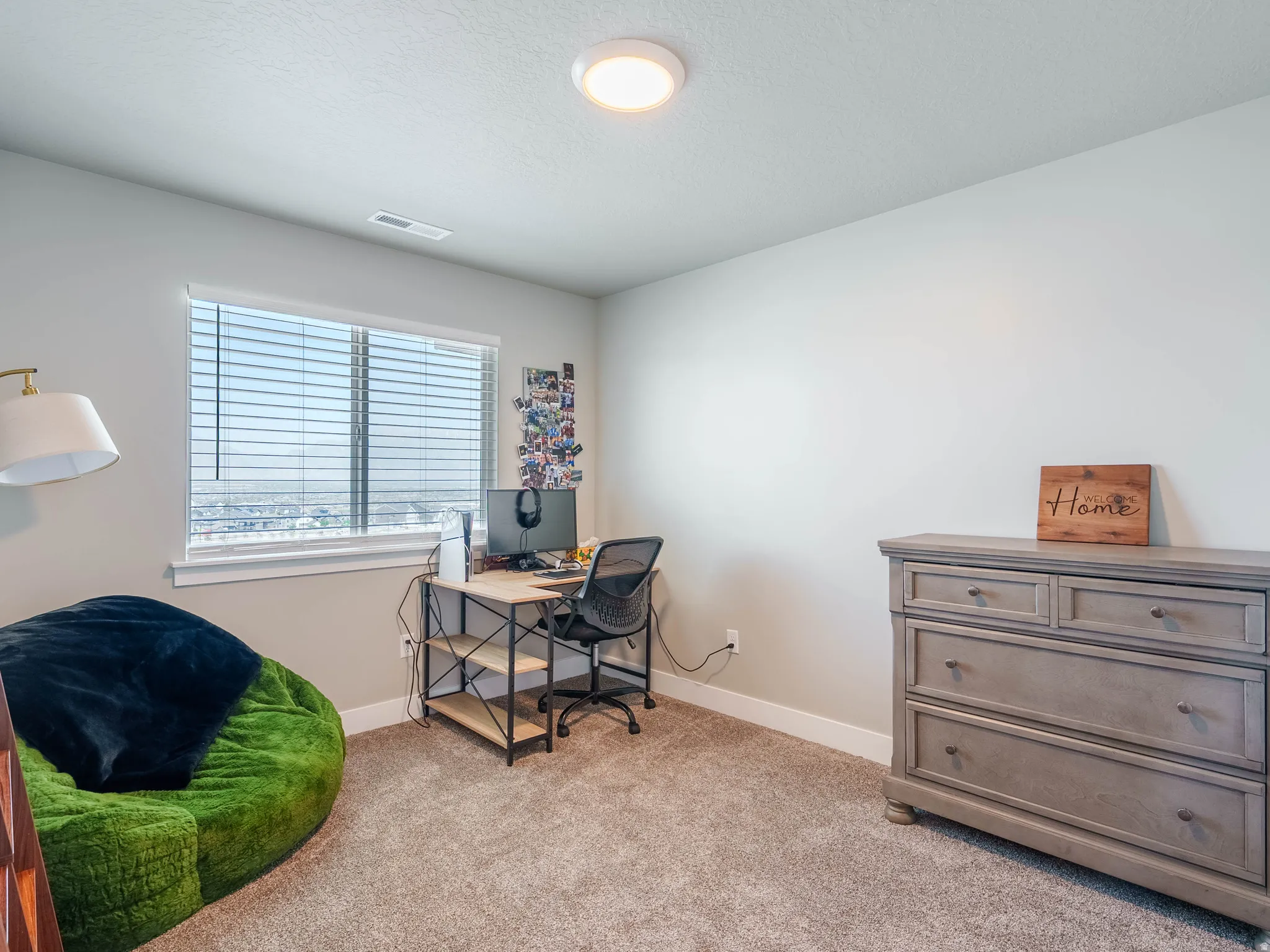 Carpeted interior room featuring a window with horizontal blinds, light gray walls, white trim, and a flush-mount ceiling light