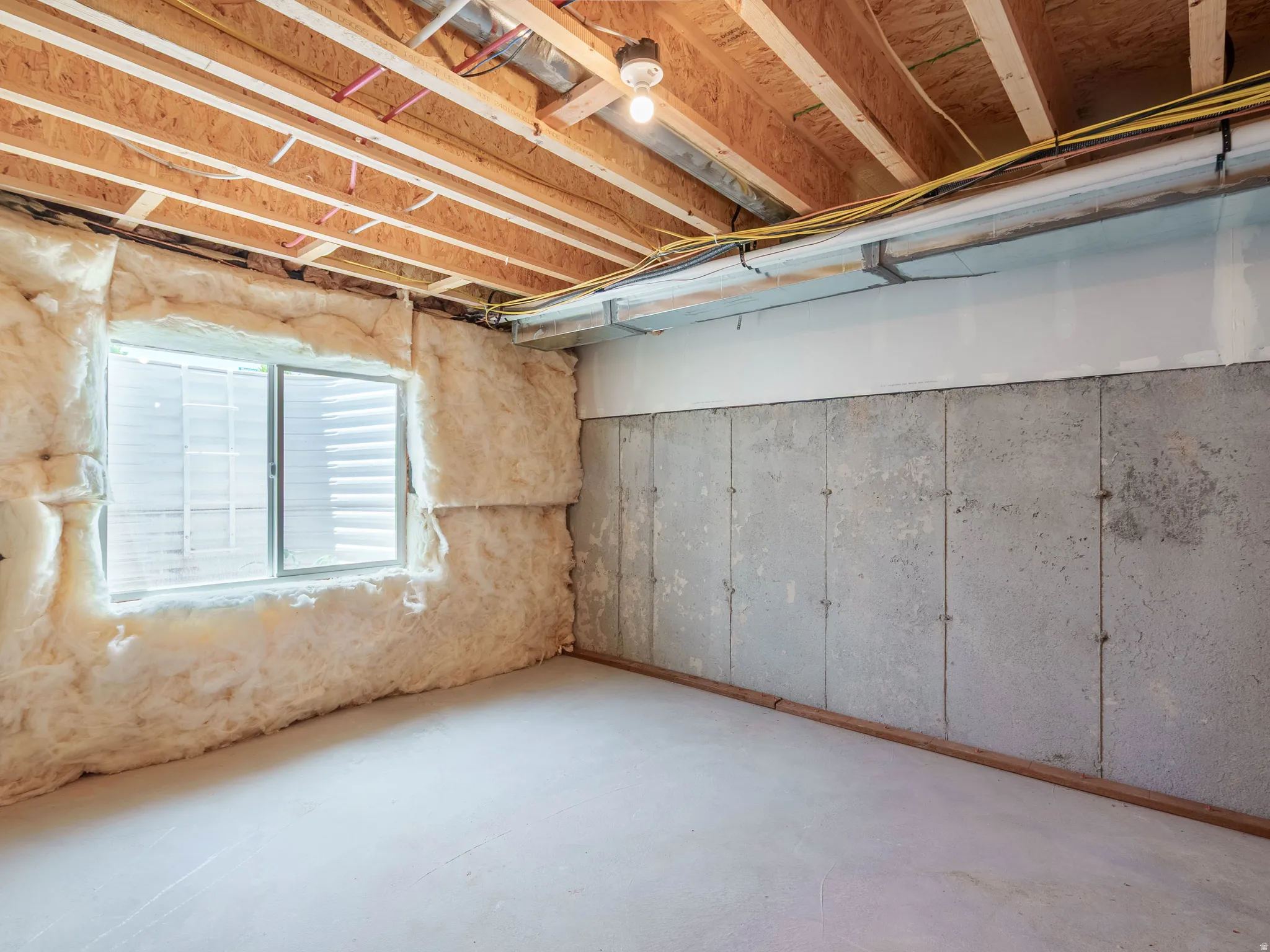 Unfinished basement area with exposed wood ceiling joists and subfloor