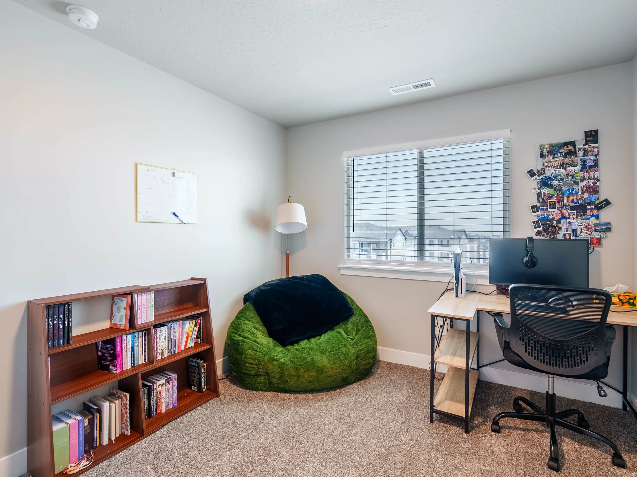 Carpeted interior room with a window featuring horizontal blinds
