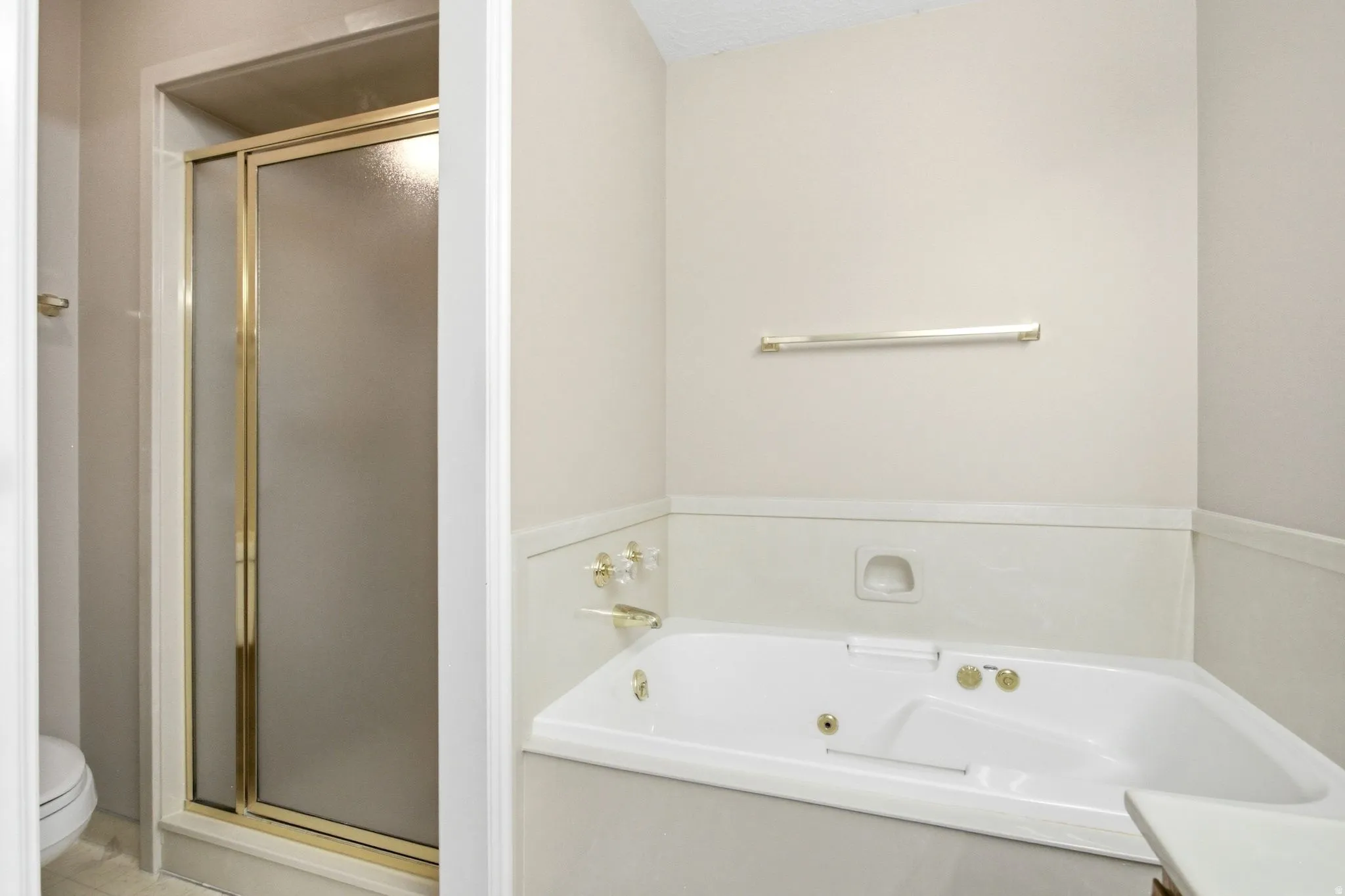 Bathroom featuring an enclosed shower with gold-tone framing and a built-in corner tub with gold-tone fixtures