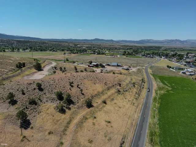 Expansive undeveloped land featuring natural desert vegetation, a paved road, and distant mountain ranges under a clear sky
