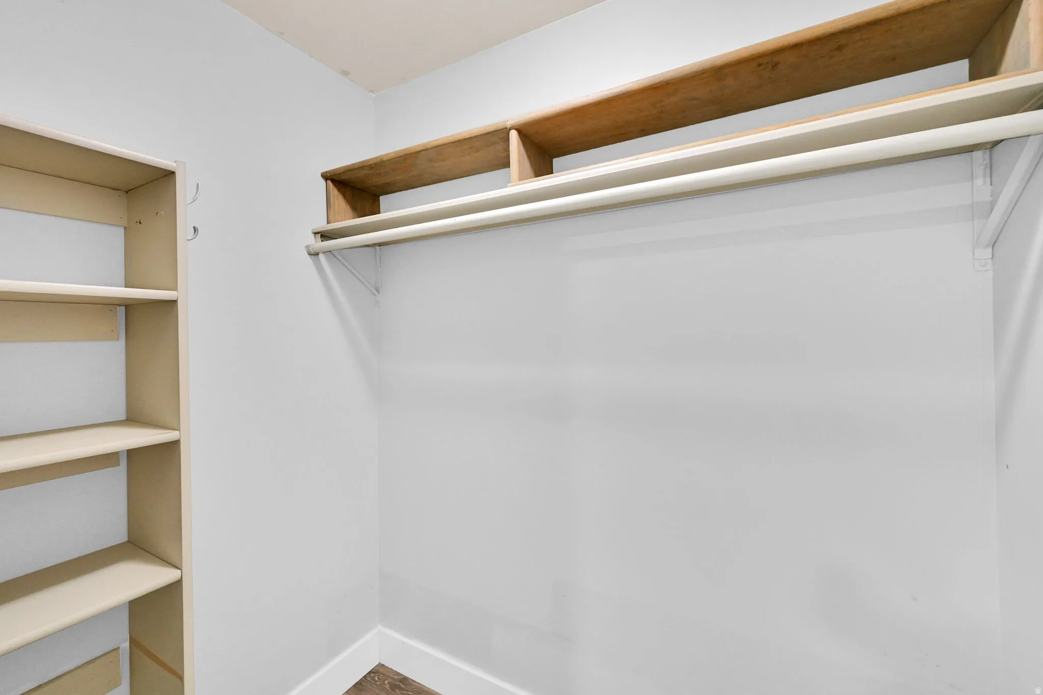 Storage space featuring a built-in shelving unit, overhead shelving, and a clothing rod