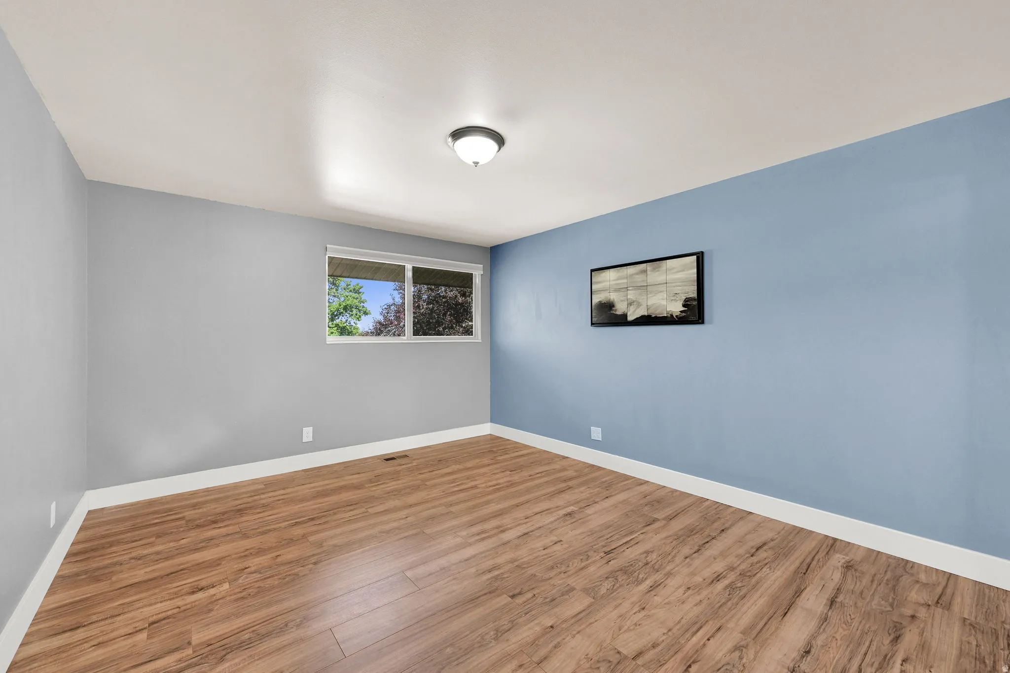 Spacious interior featuring wood-finish flooring, light blue and gray wall tones, and white trim