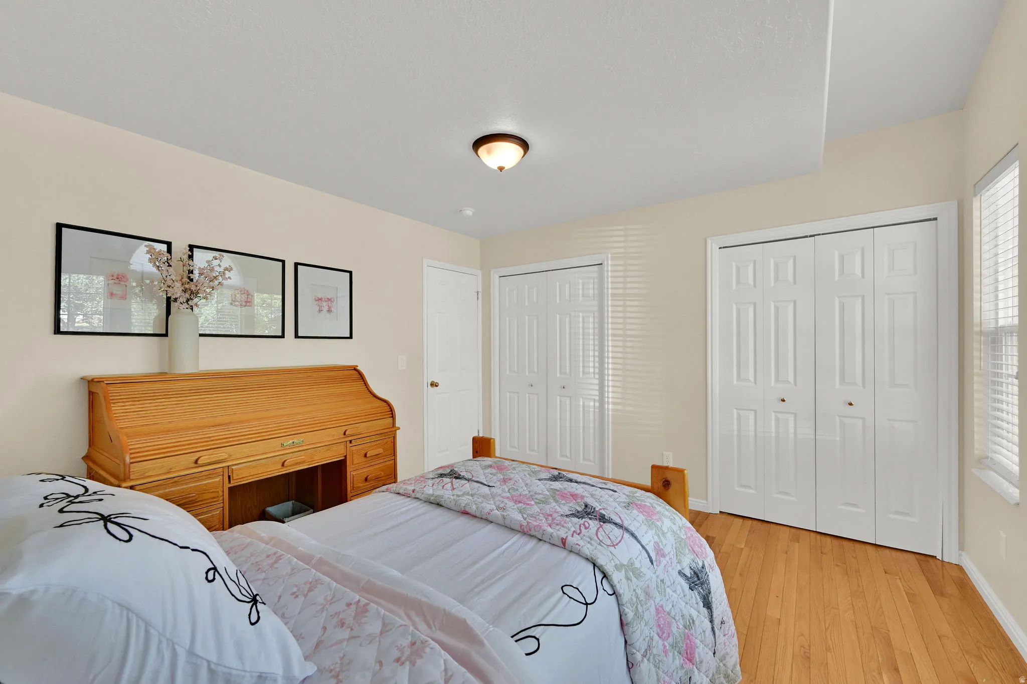 Bedroom featuring light wood-finish flooring, light-colored walls, and a tray ceiling