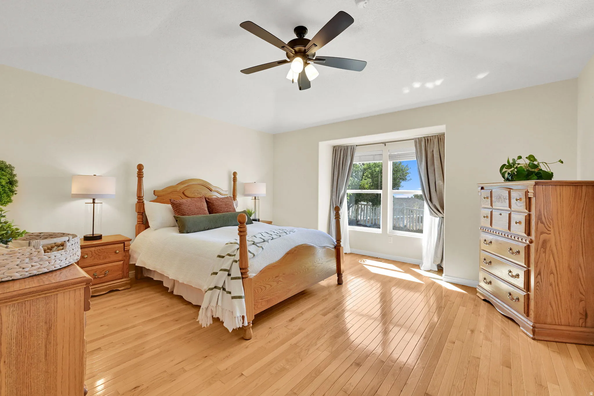 Expansive room featuring light wood-finish flooring, a large window with exterior visibility, a ceiling fan with integrated lighting, and neutral wall tones