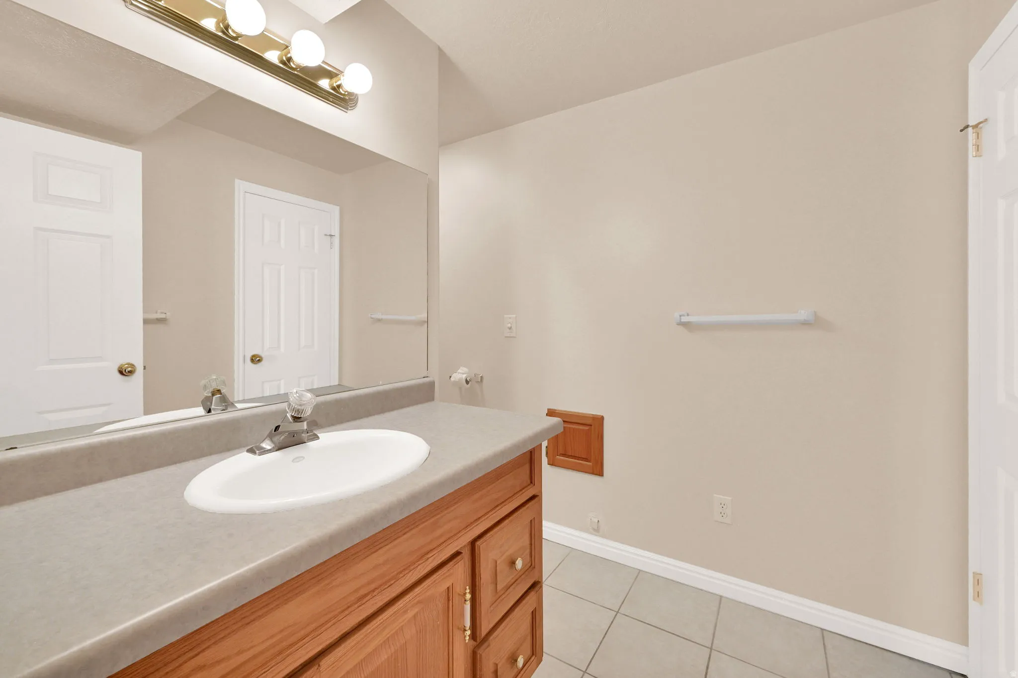 Bathroom featuring a wood-finish vanity with a single basin sink and a gray countertop