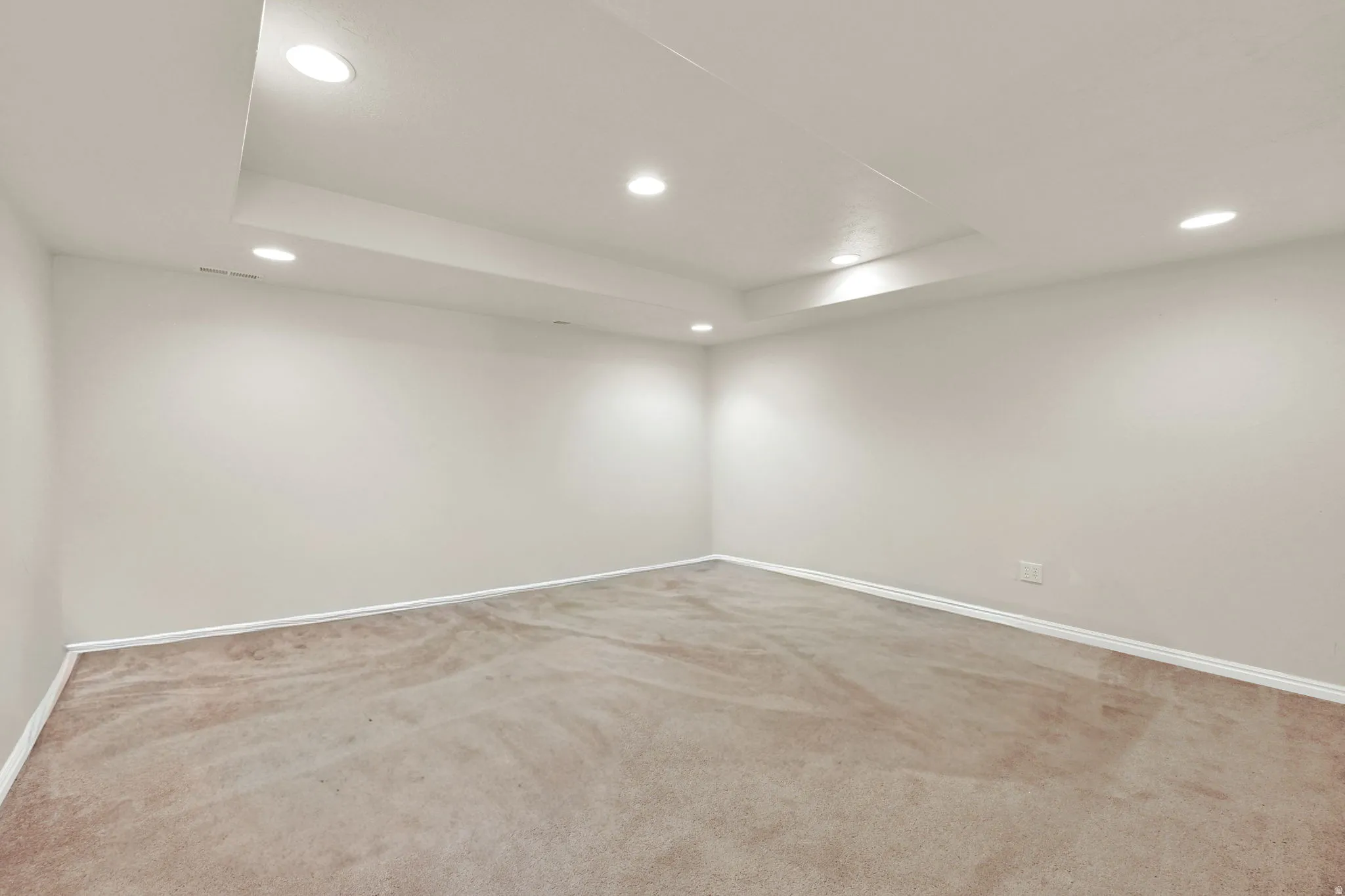 Spacious room featuring neutral carpeting, light-toned walls, and recessed lighting
