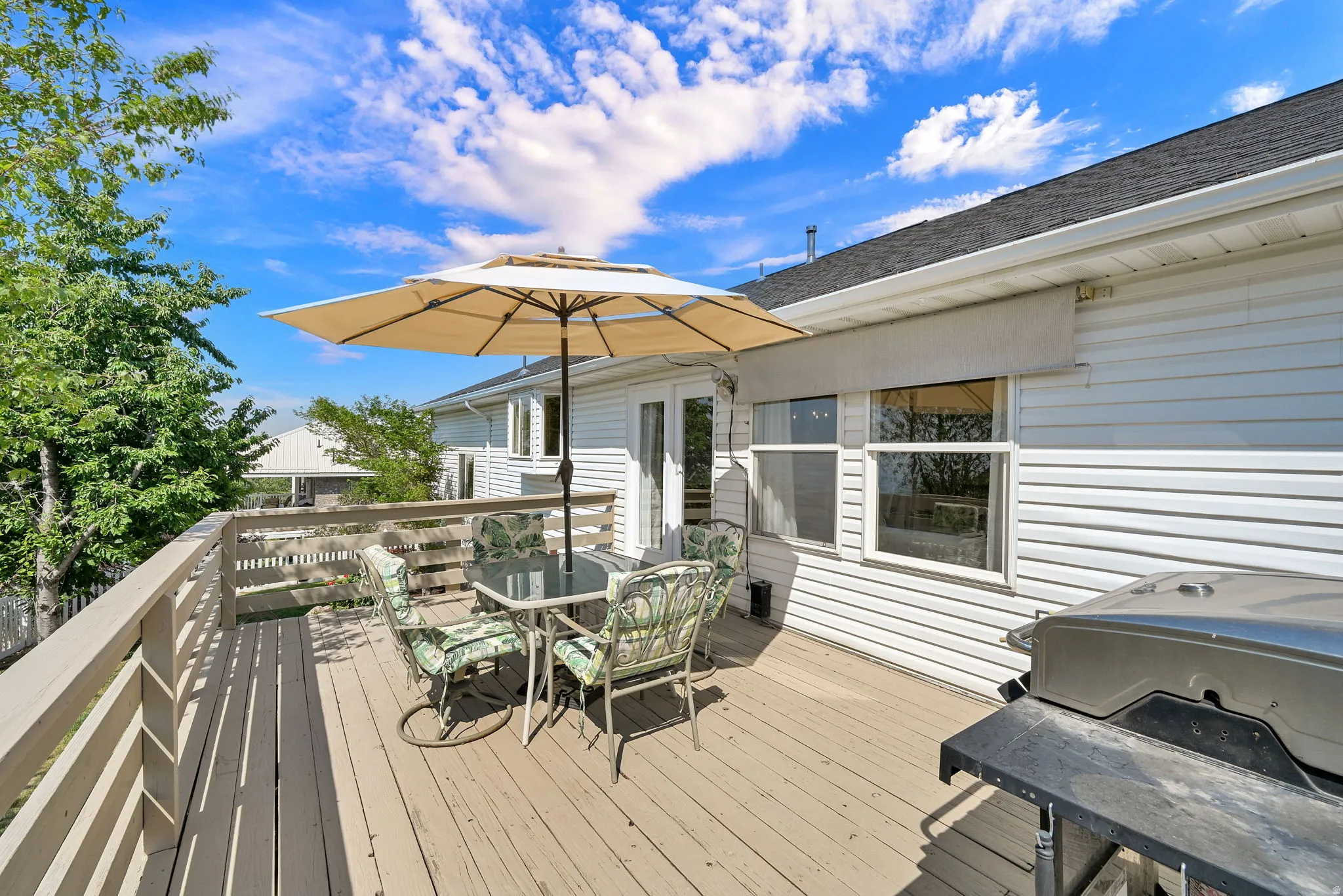 Outdoor deck featuring wood-finish flooring, white siding, and a dark shingle roof