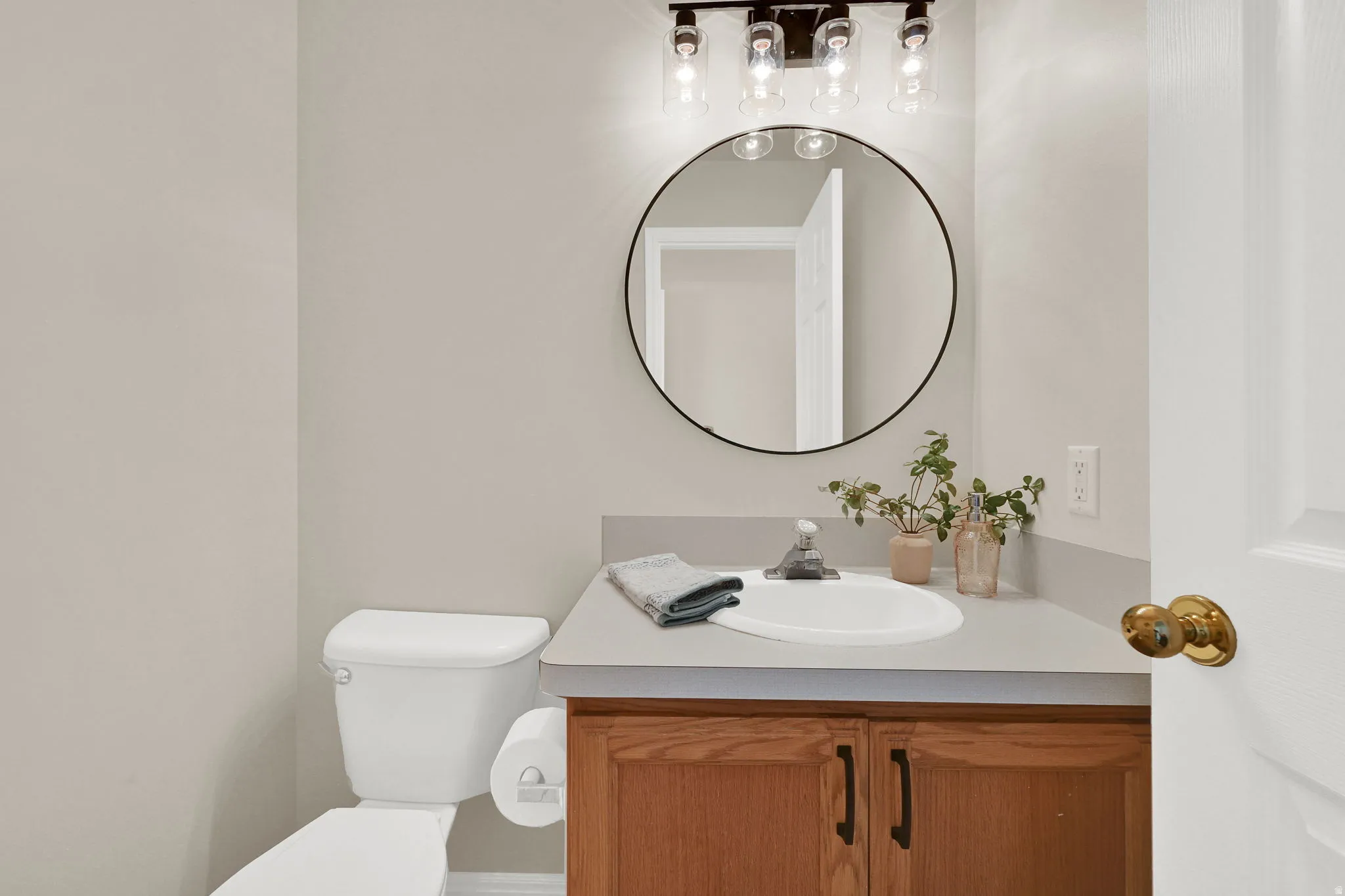 Bathroom featuring a vanity with a light-toned countertop, an integrated sink, and wood-finish cabinetry with dark hardware
