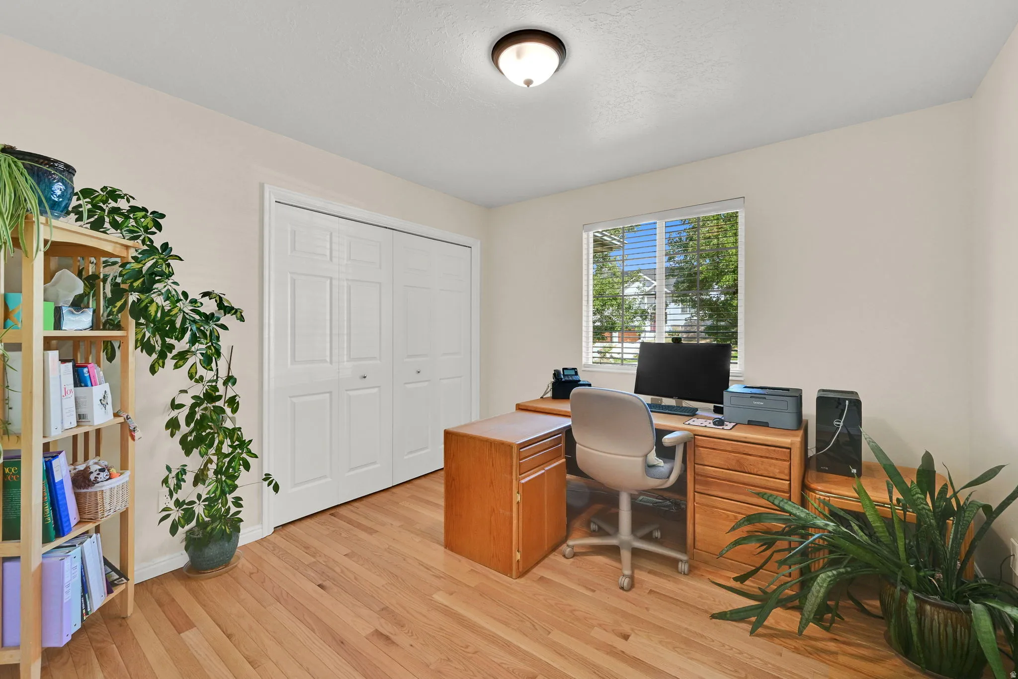 Room featuring wood-finish flooring, light-toned walls, and a window with blinds