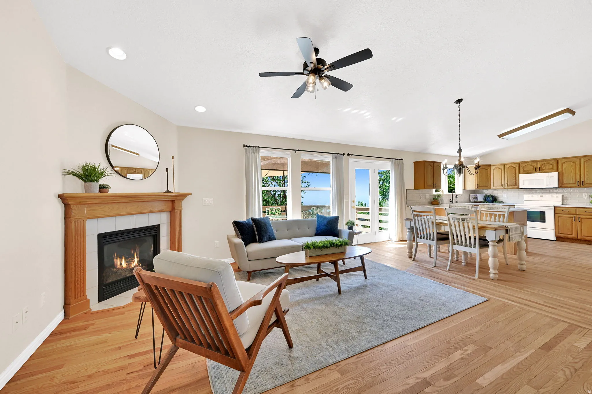 Open-concept living space featuring wood-finish flooring, a fireplace with a wood mantle and tile surround, and recessed lighting