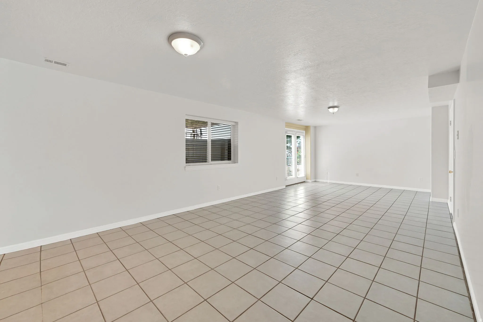 Spacious room featuring light-toned square tile flooring and white walls