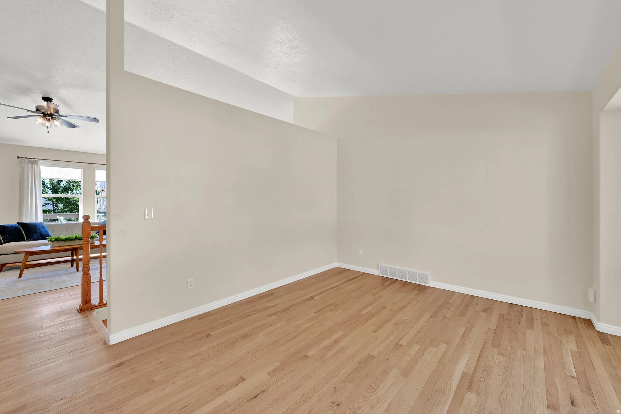 Spacious room with wood-finish flooring, light neutral wall paint, and white baseboards
