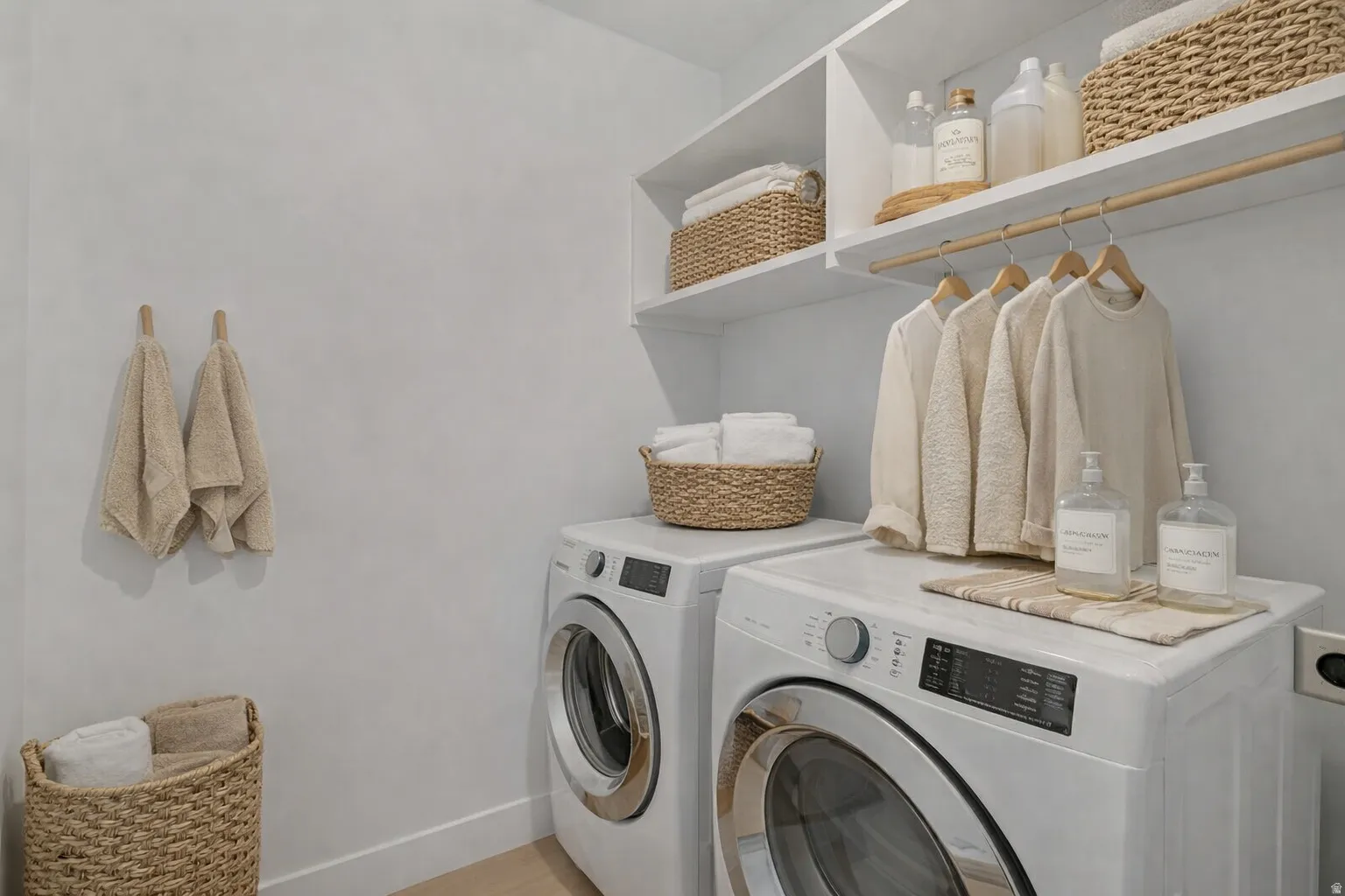 Dedicated laundry area featuring a front-loading washer and dryer, integrated shelving, and a hanging rod