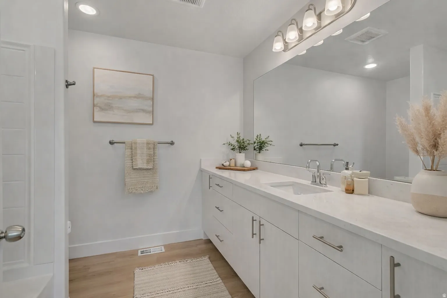 Bathroom featuring an extended vanity with dual sinks, light-toned countertops, and ample under-cabinet storage