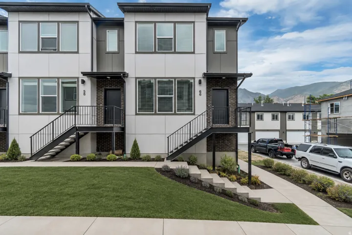 Contemporary townhome exterior featuring white and dark gray paneling, large windows, and a dark brick accent wall