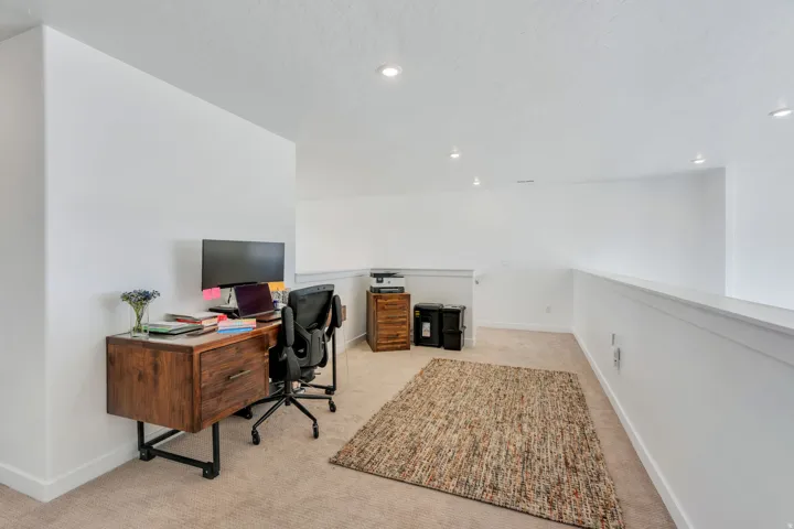 Carpeted loft space featuring bright white walls and recessed ceiling lighting