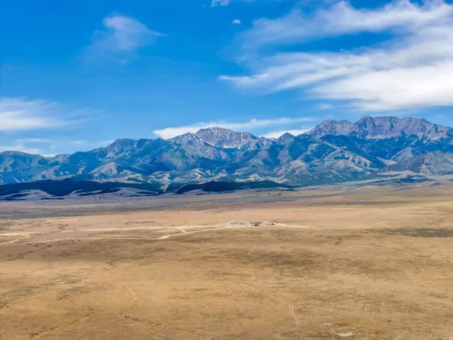 Expansive open landscape with distant mountain ranges under a blue sky with scattered clouds