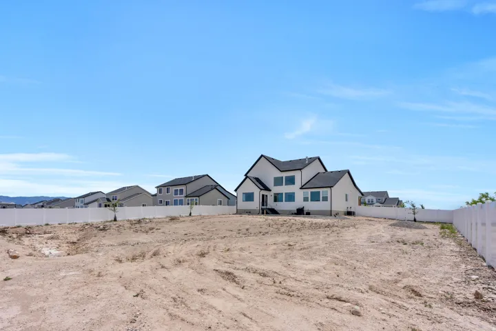 Expansive land parcel with a new construction home featuring white siding, a dark roof, multiple windows, and a white perimeter fence
