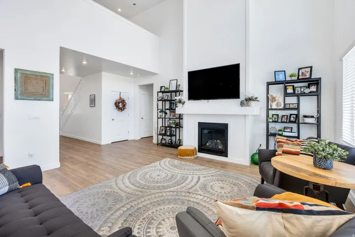 Vaulted living space featuring wood-finish flooring, a white fireplace with a mantel, and recessed lighting