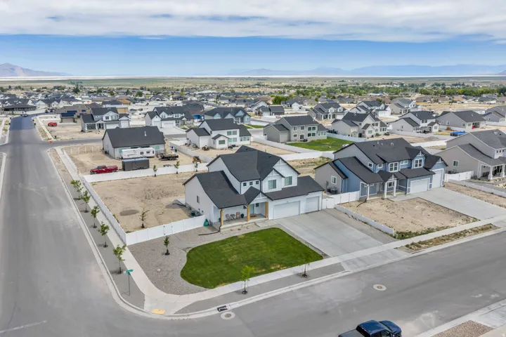 Expansive residential development featuring modern homes with dark roofs, concrete driveways, and landscaped front yards