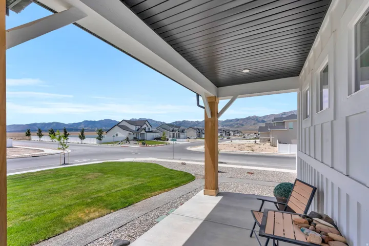 Covered front porch featuring a dark slatted ceiling, recessed lighting, and a prominent wood-finish support beam