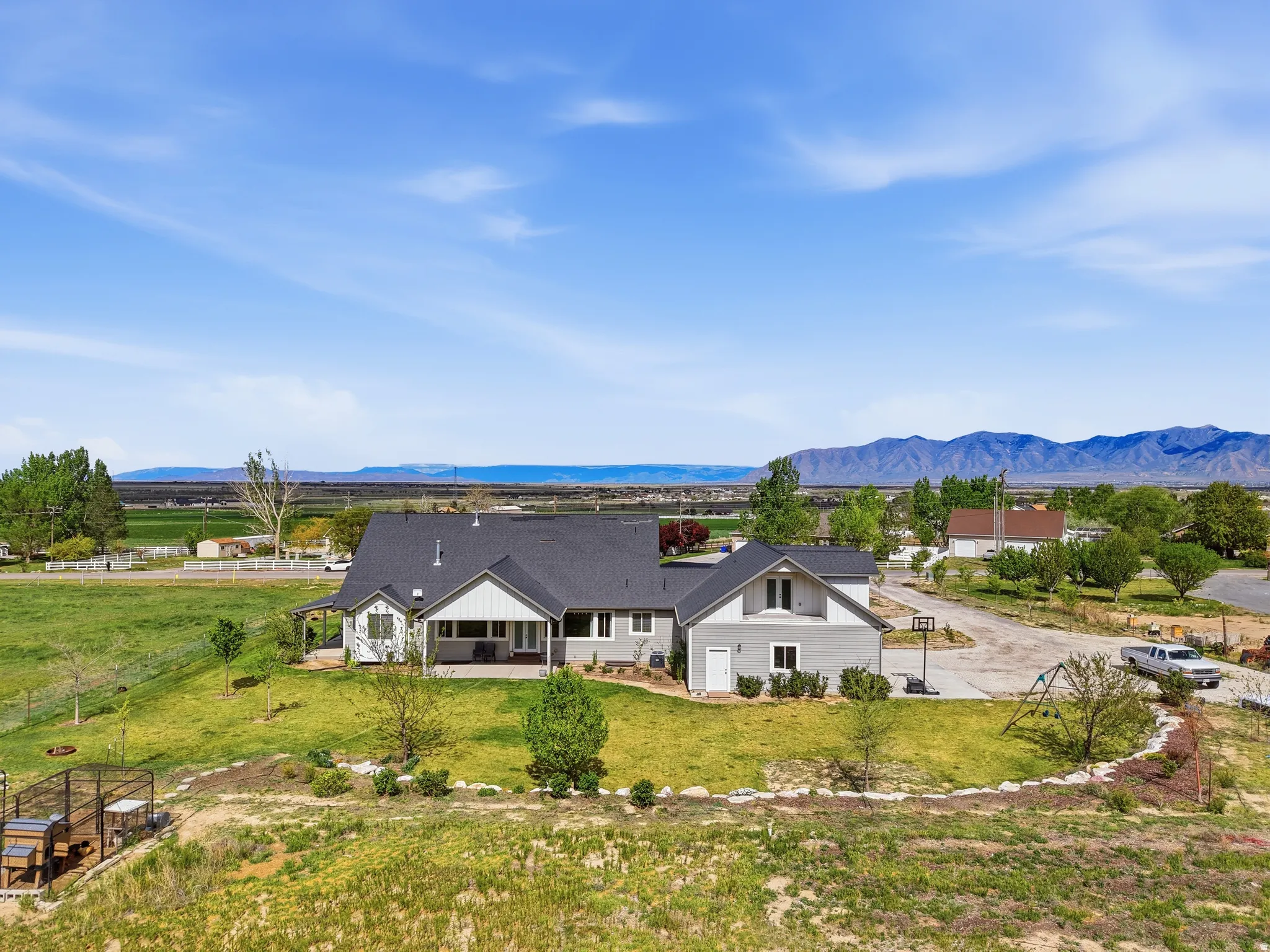 Expansive property featuring a single-story residence with a dark shingle roof and light gray siding