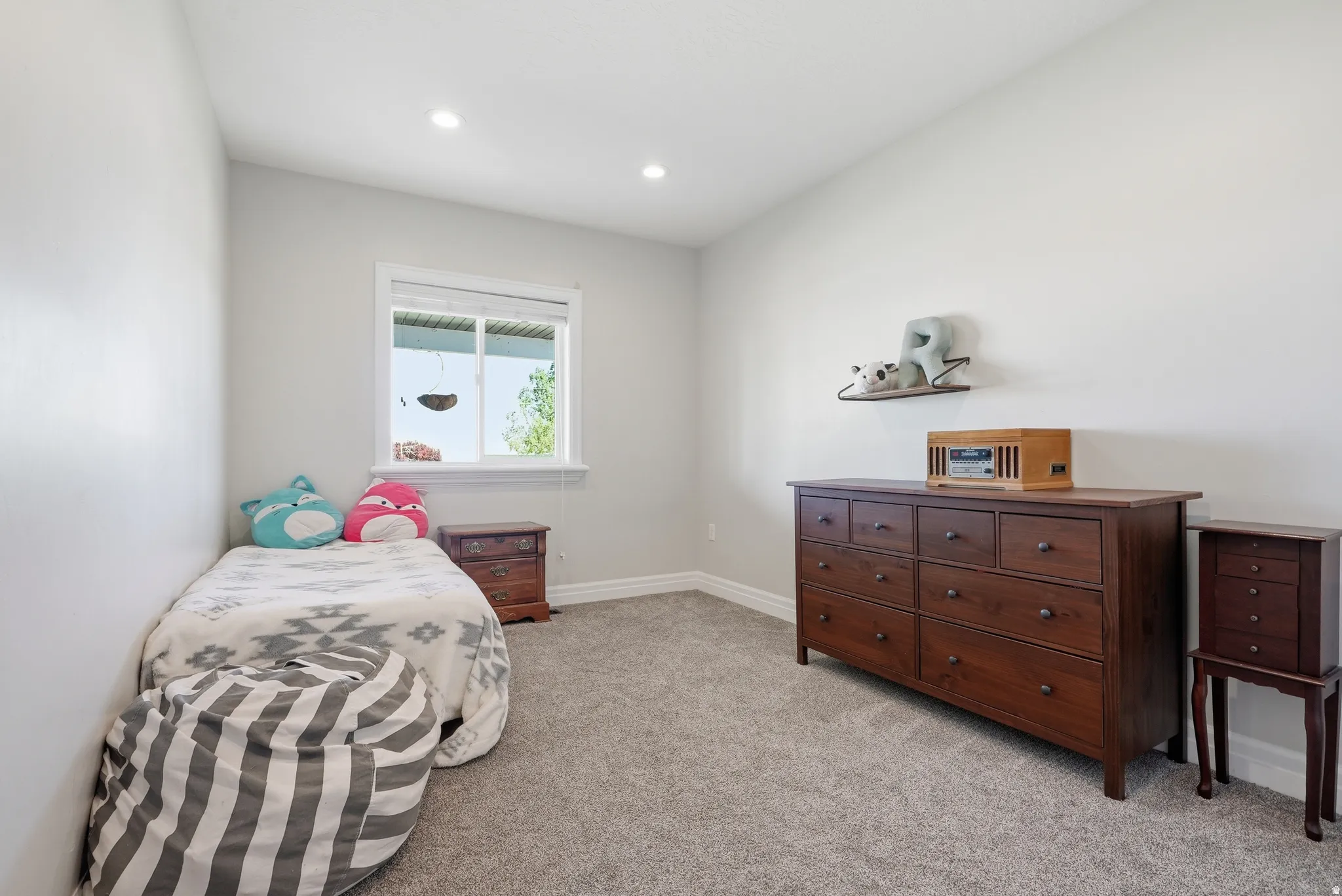 Bright room featuring light gray wall paint, gray carpet flooring, a white-trimmed window, and recessed lighting fixtures