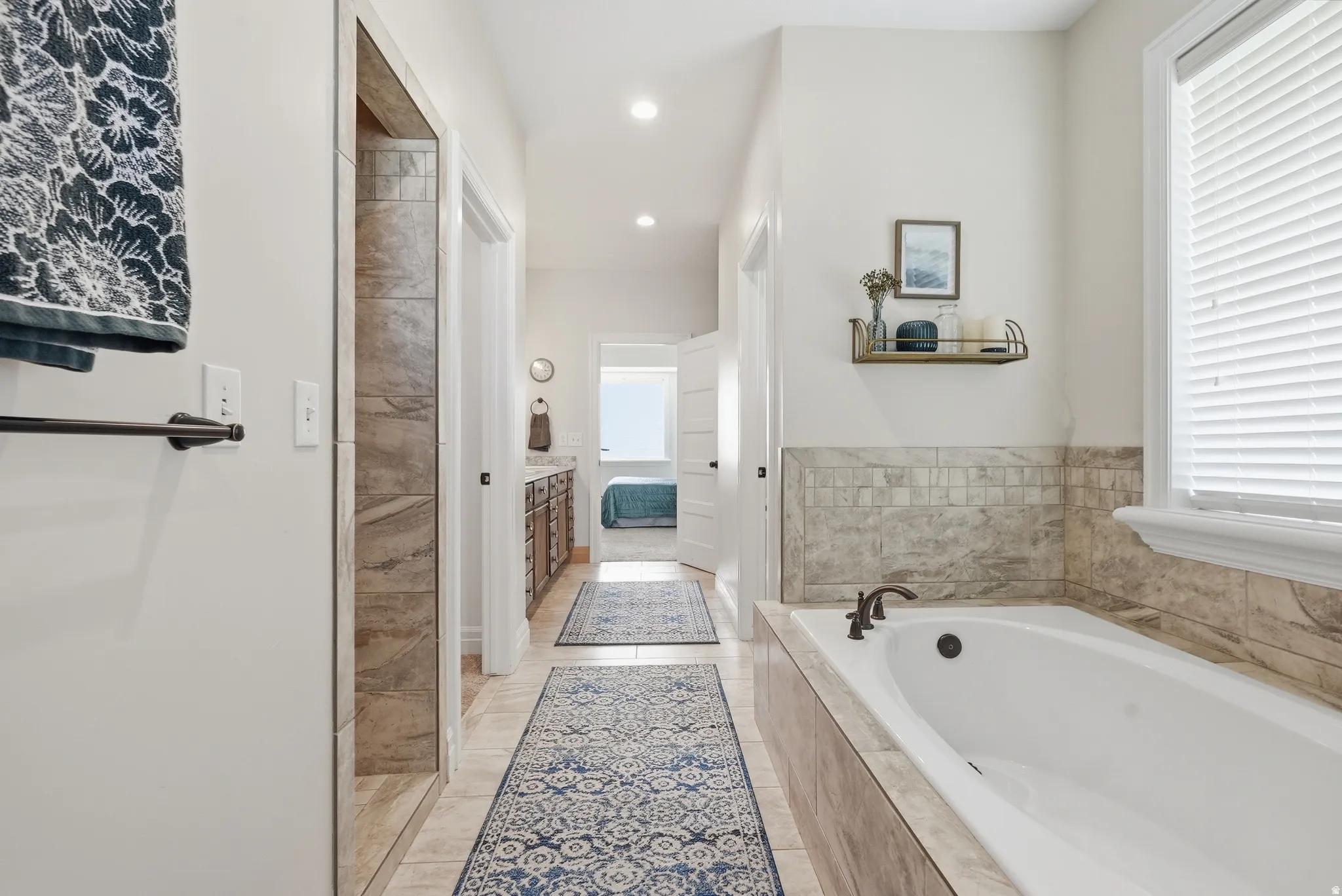Spacious bathroom featuring an integrated soaking tub with an oil-rubbed bronze faucet, a tiled shower enclosure, and vanity with built-in cabinetry