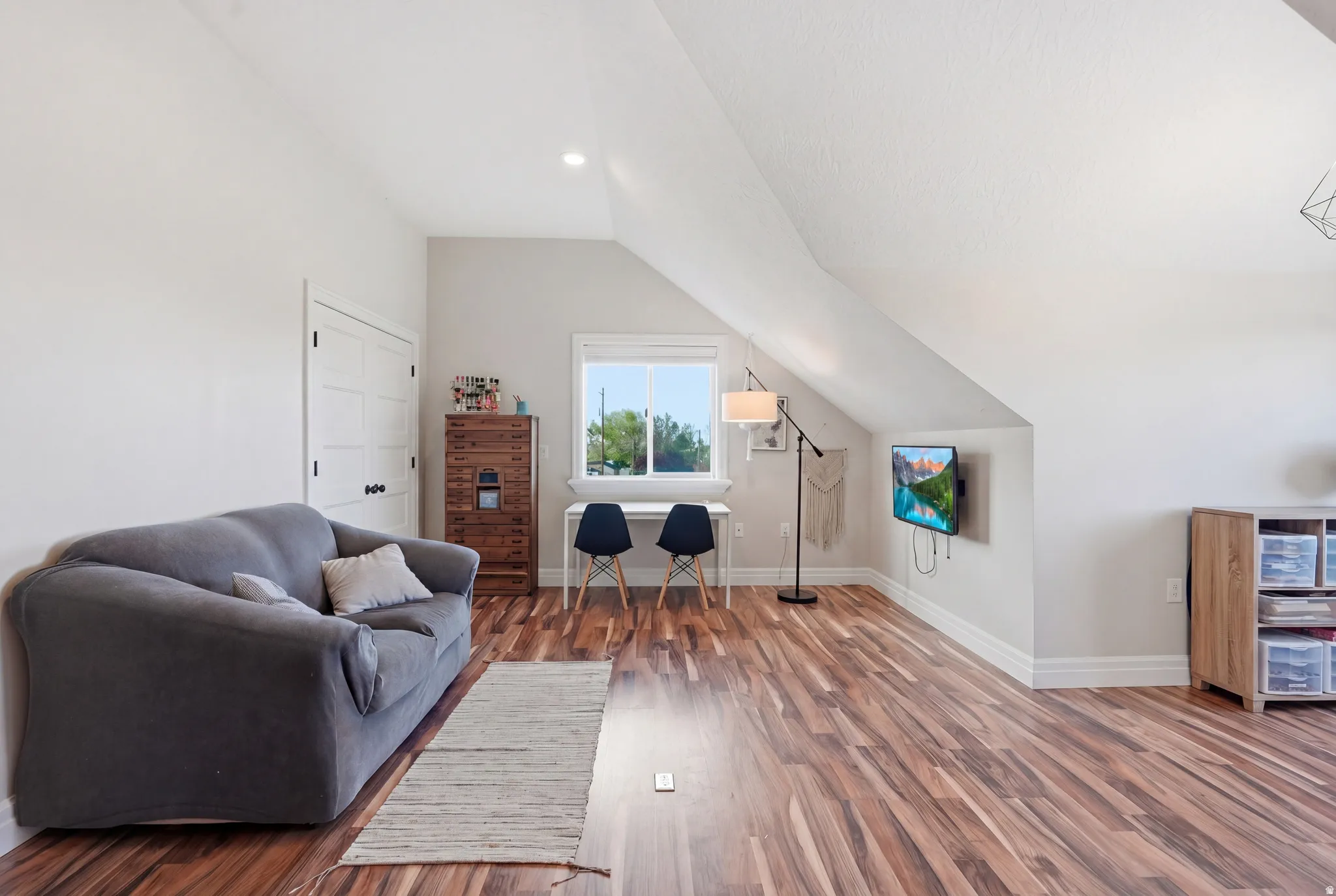 Versatile bonus room featuring wood-finish flooring and a vaulted ceiling