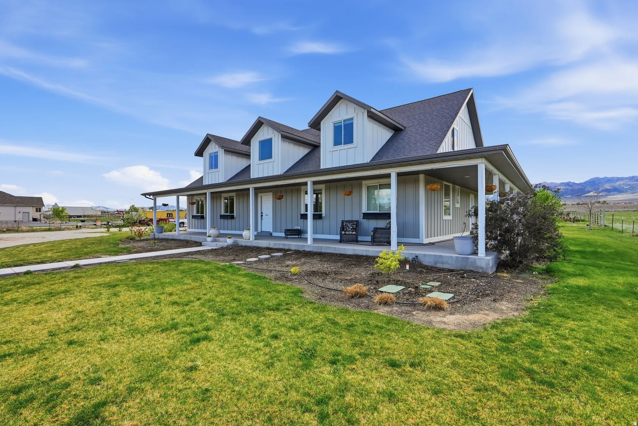 Farmhouse-style residence featuring a covered front porch, dormer windows, and horizontal siding