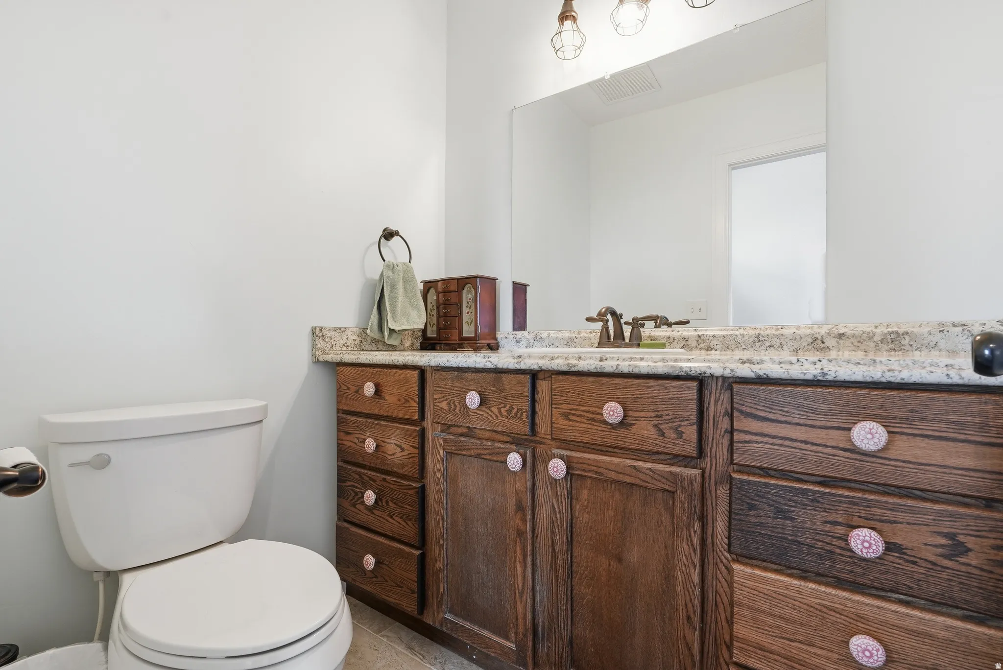 Bathroom vanity featuring a light-toned countertop, integrated sink, and an expansive mirror