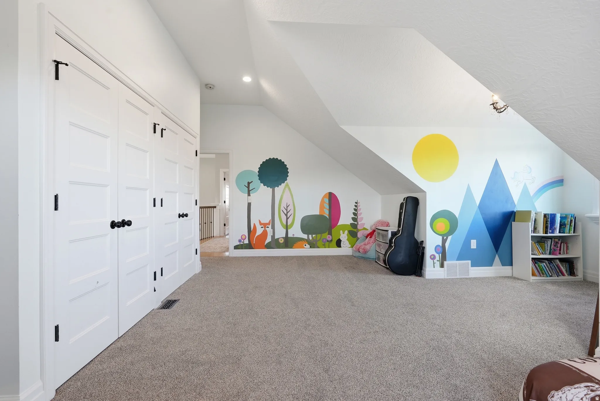 Spacious carpeted room featuring white paneled closet doors with matte black hardware, sloped ceilings, and recessed lighting