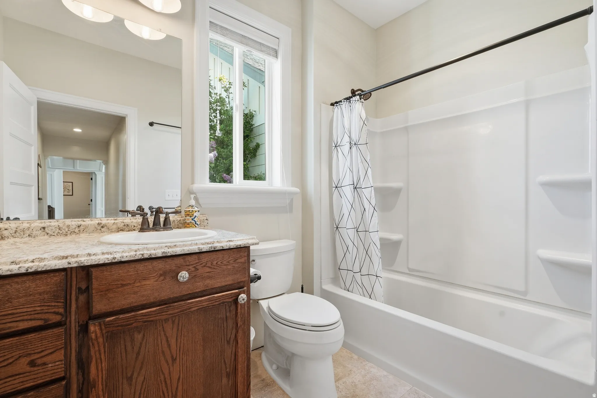 Bathroom featuring a wood-finish vanity with a light-toned countertop, an integrated sink, and a mirrored wall