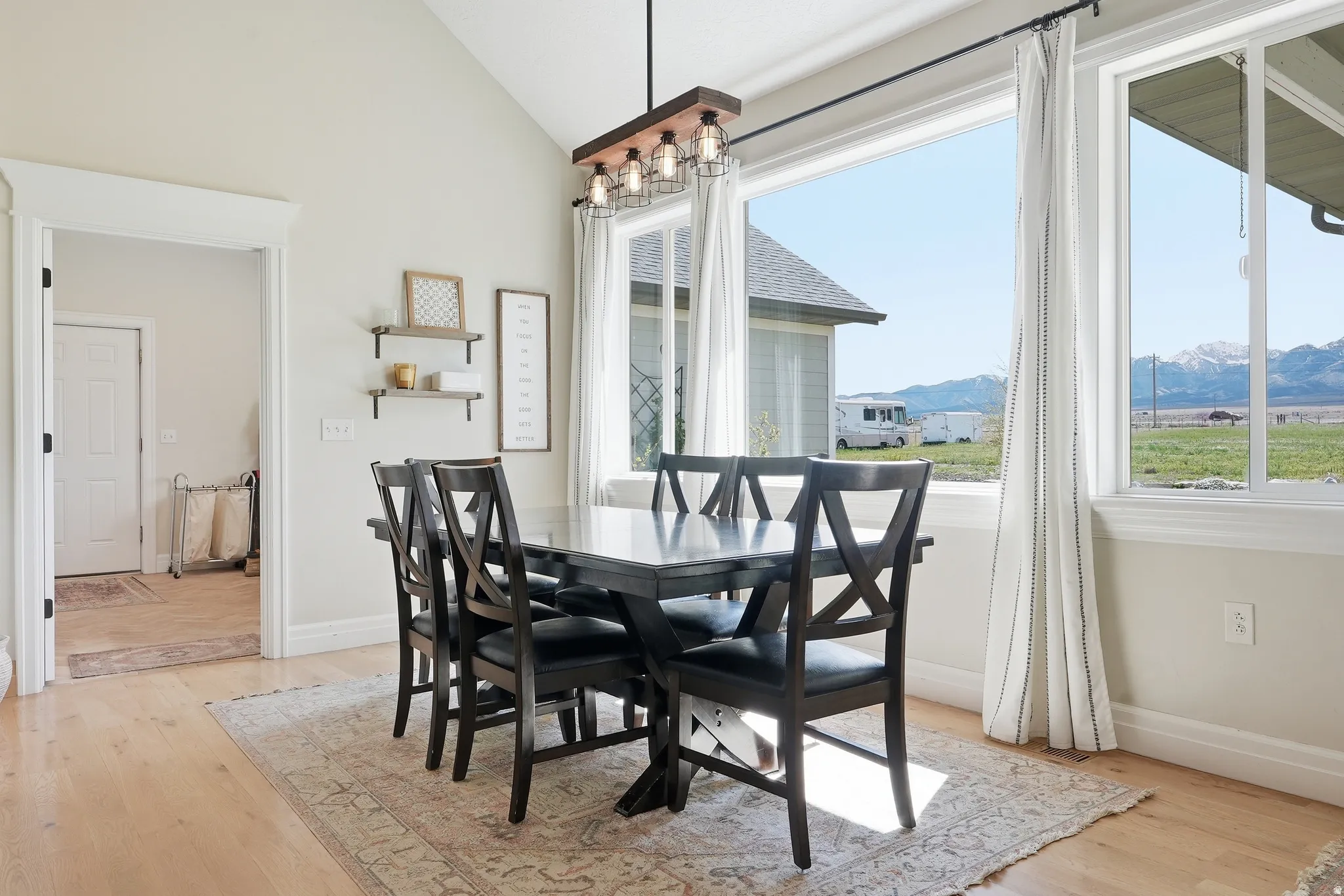 Dining area featuring a vaulted ceiling, light wood-finish flooring, and expansive windows