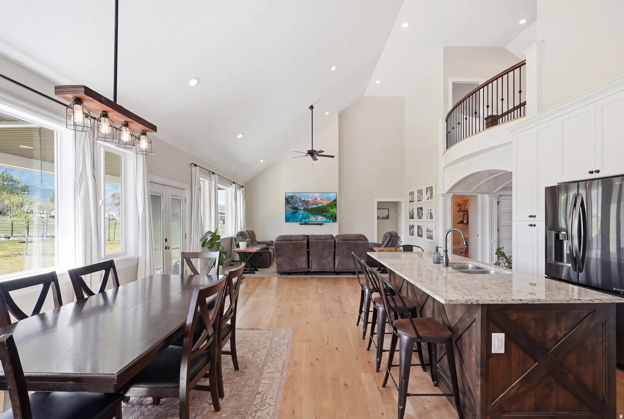 Open-concept interior featuring vaulted ceilings with recessed lighting, wood-finish flooring, and a kitchen island with stone countertops and dark wood paneling