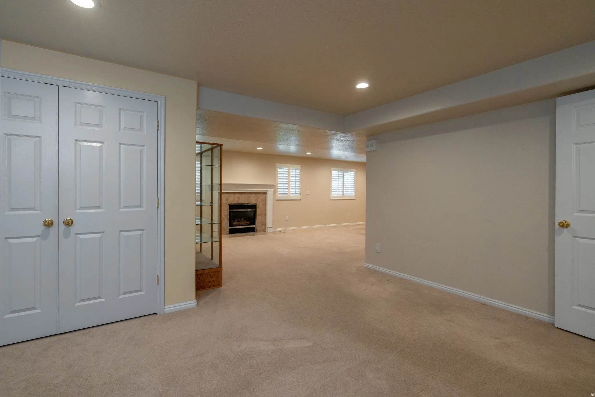 Spacious room featuring neutral carpeting, recessed lighting, and white baseboards