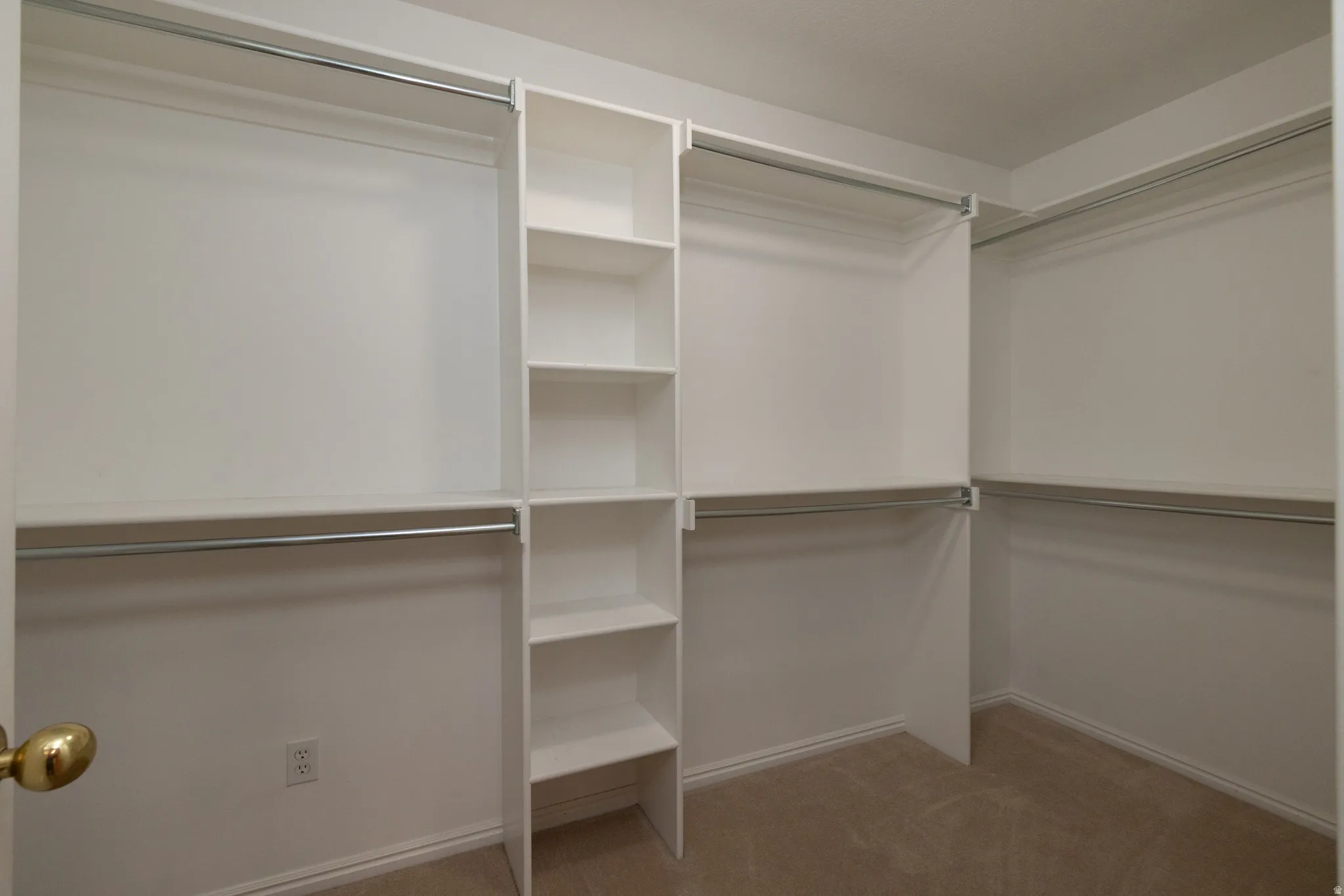 Walk-in closet featuring built-in shelving, multiple hanging rods, and neutral-toned carpeting