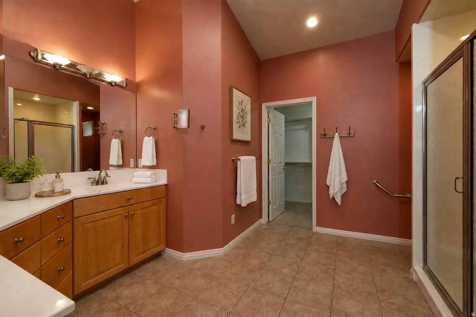 Virtually Staged - Spacious master bathroom featuring a dual vanity with wood cabinetry, a white countertop, and an integrated mirror. Walk in closet.