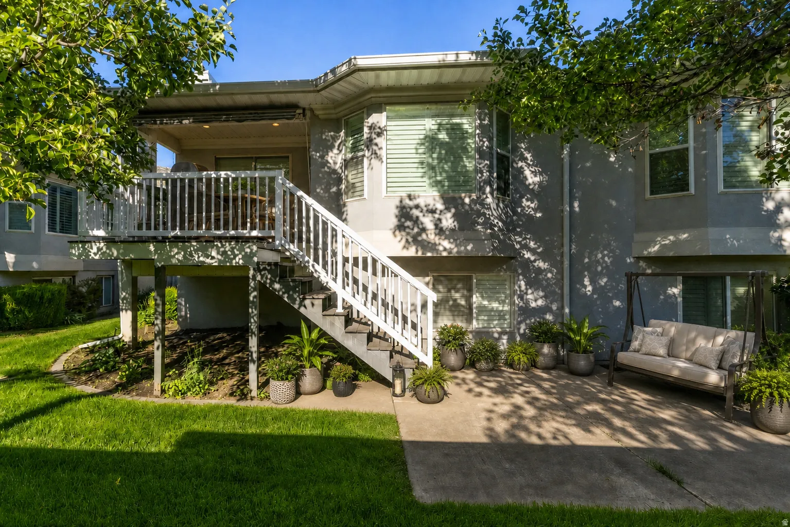Virtually Staged - Rear exterior featuring a multi-level deck, a concrete patio, and a manicured lawn