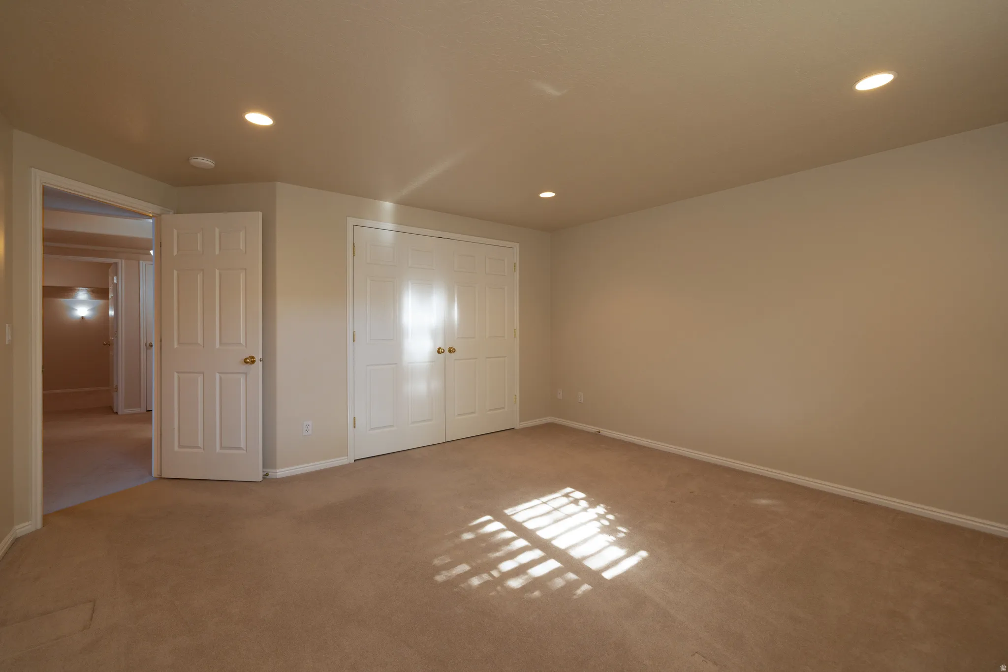 Carpeted room featuring multiple recessed ceiling lights, neutral wall tones, and white baseboards