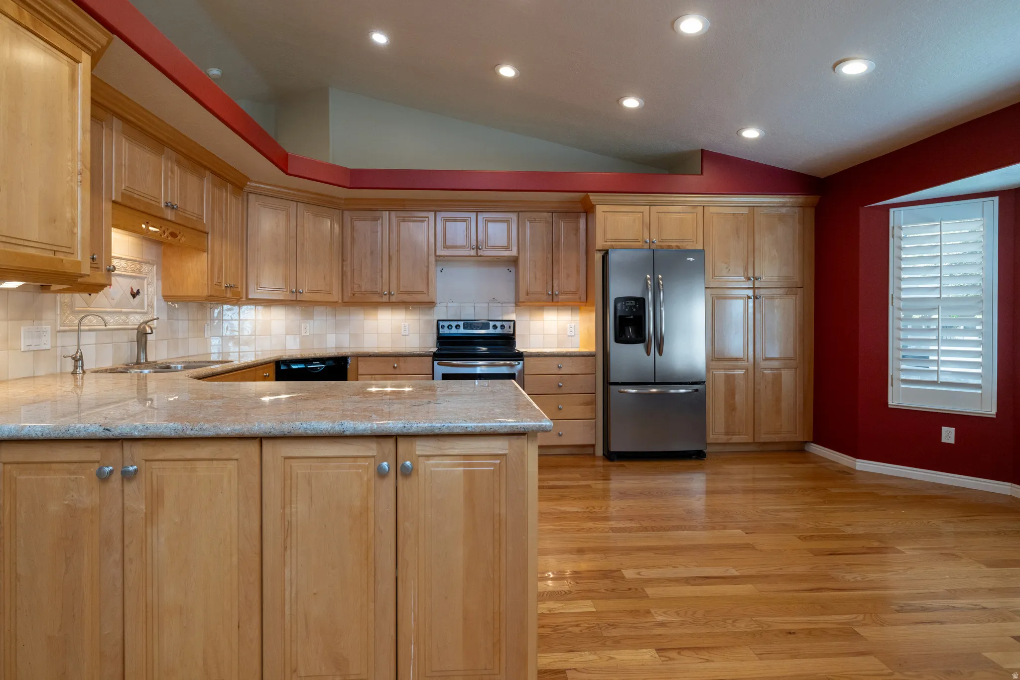 Kitchen featuring light wood cabinetry, light-toned countertops, stainless steel appliances, and wood-finish flooring