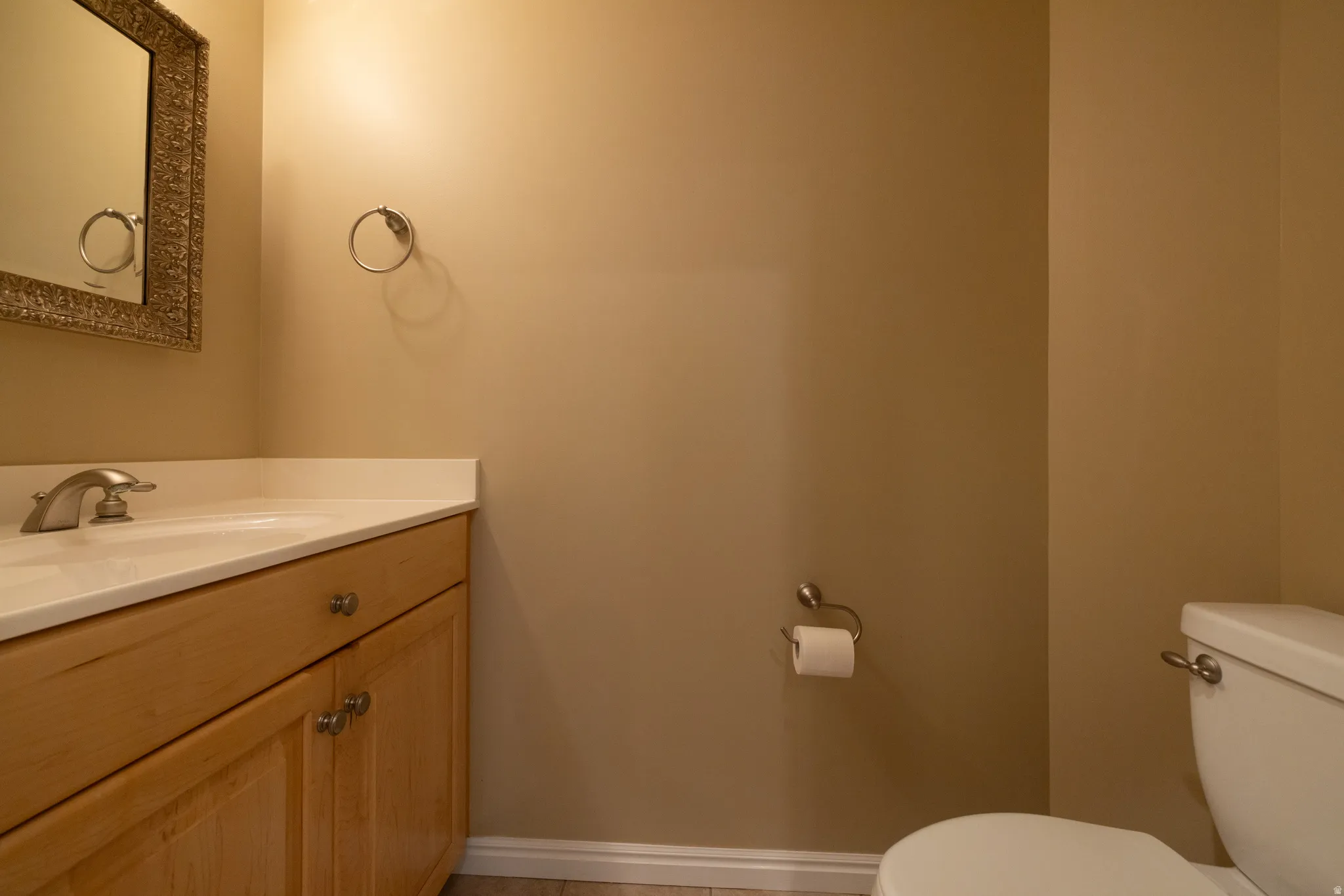 Bathroom featuring a light wood-finish vanity with a single basin sink, light-toned countertop, and brushed nickel hardware