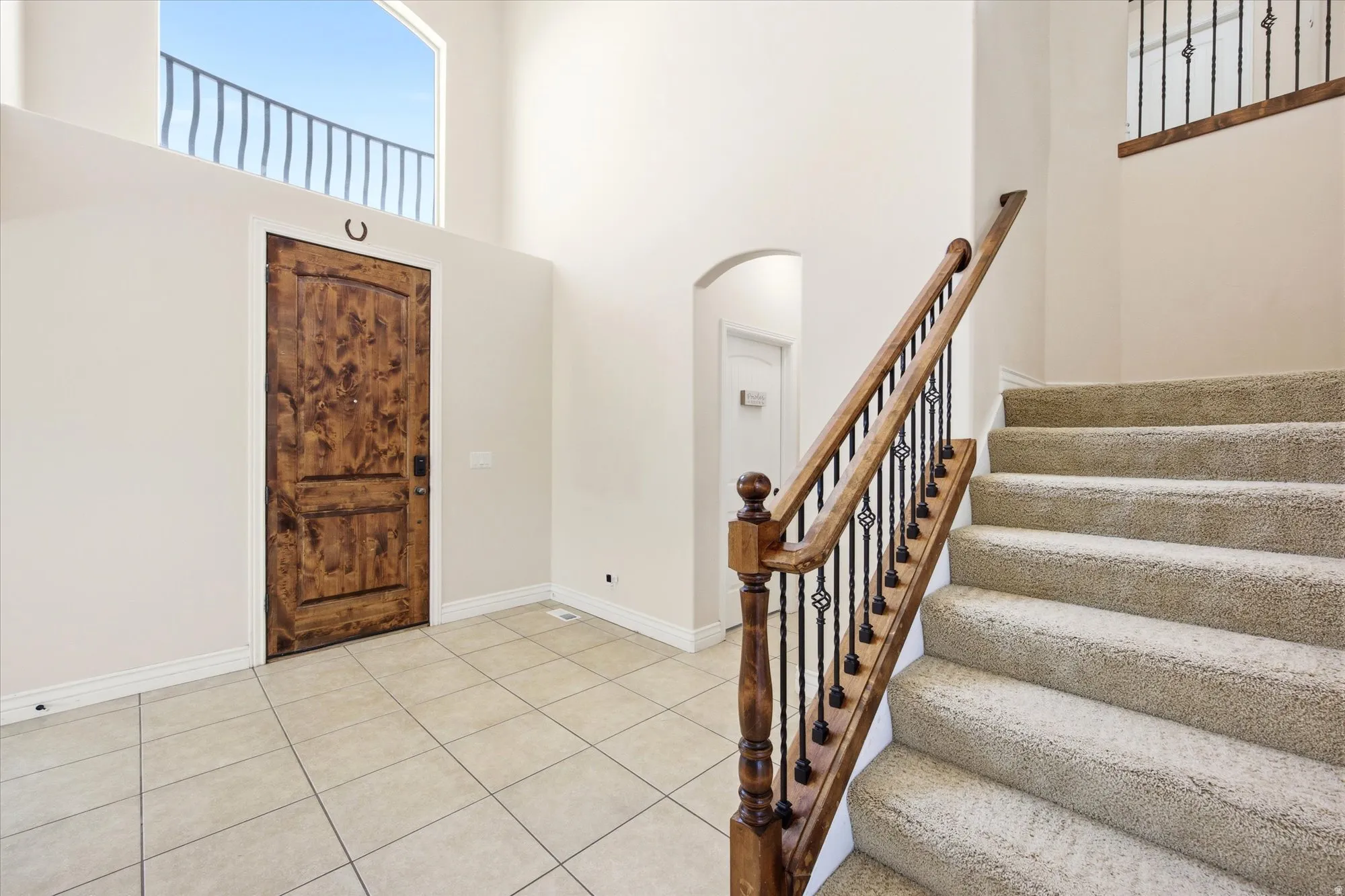 Entryway featuring a wood-finish door with white trim, a double-height ceiling, and light-colored tile flooring