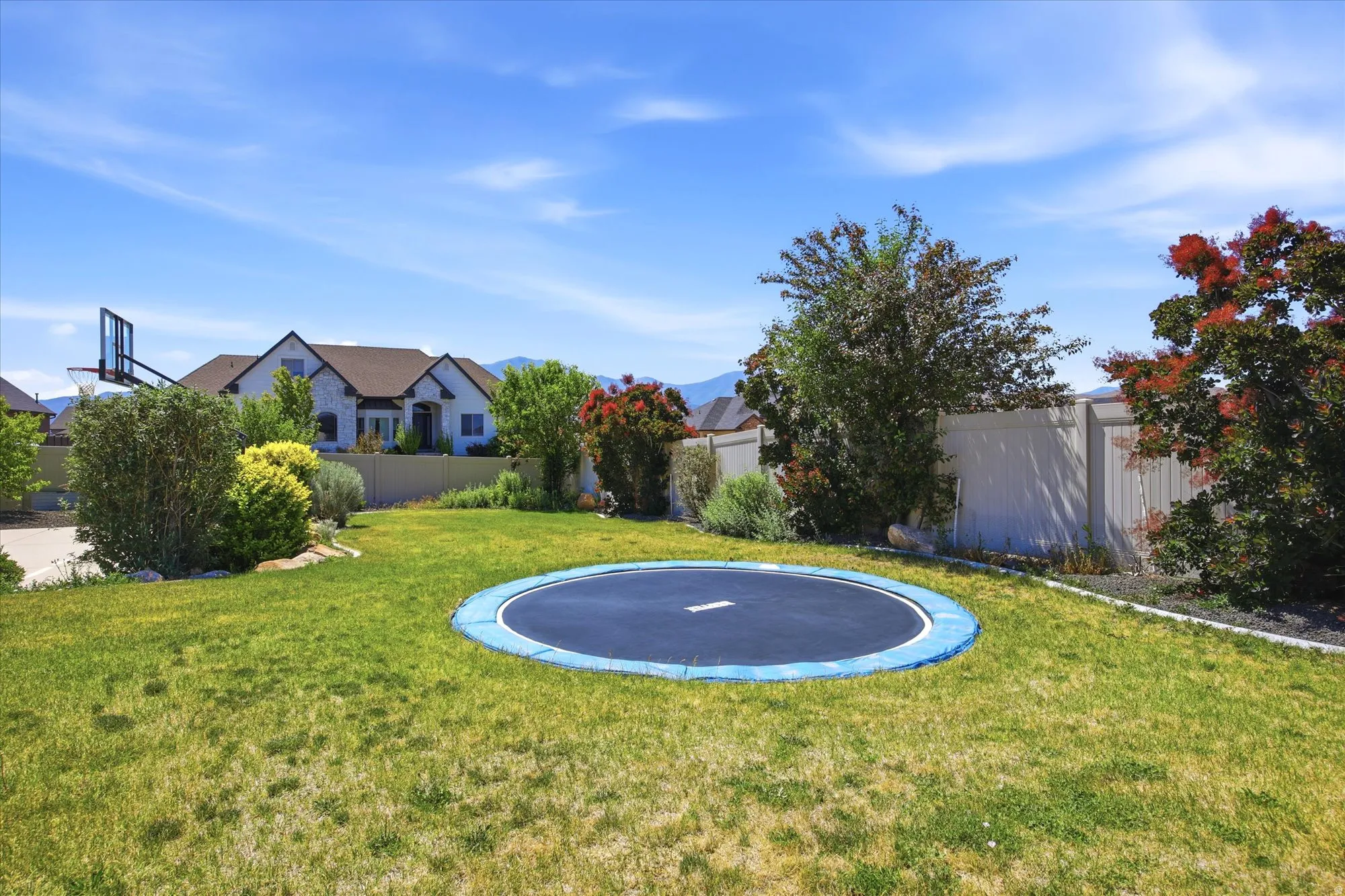 Spacious backyard featuring a manicured lawn, perimeter fencing, and mature trees