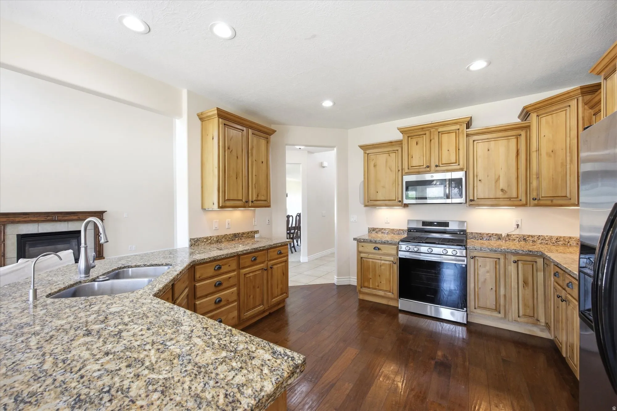 Kitchen featuring wood cabinetry, granite countertops, stainless steel appliances, a double basin sink, and recessed lighting