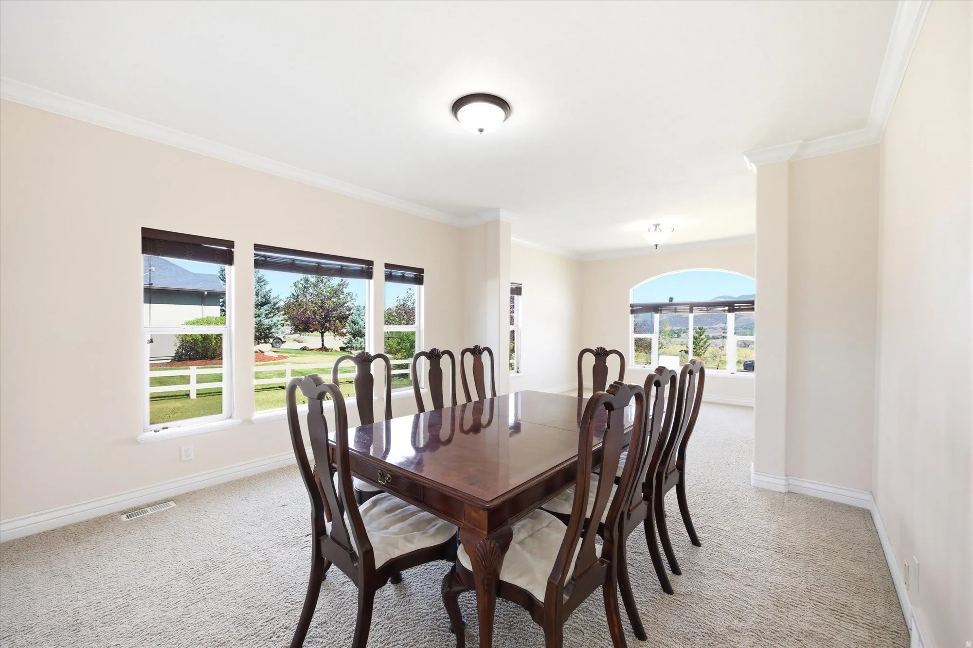 Formal dining space featuring light-toned walls, crown molding, and plush carpeting
