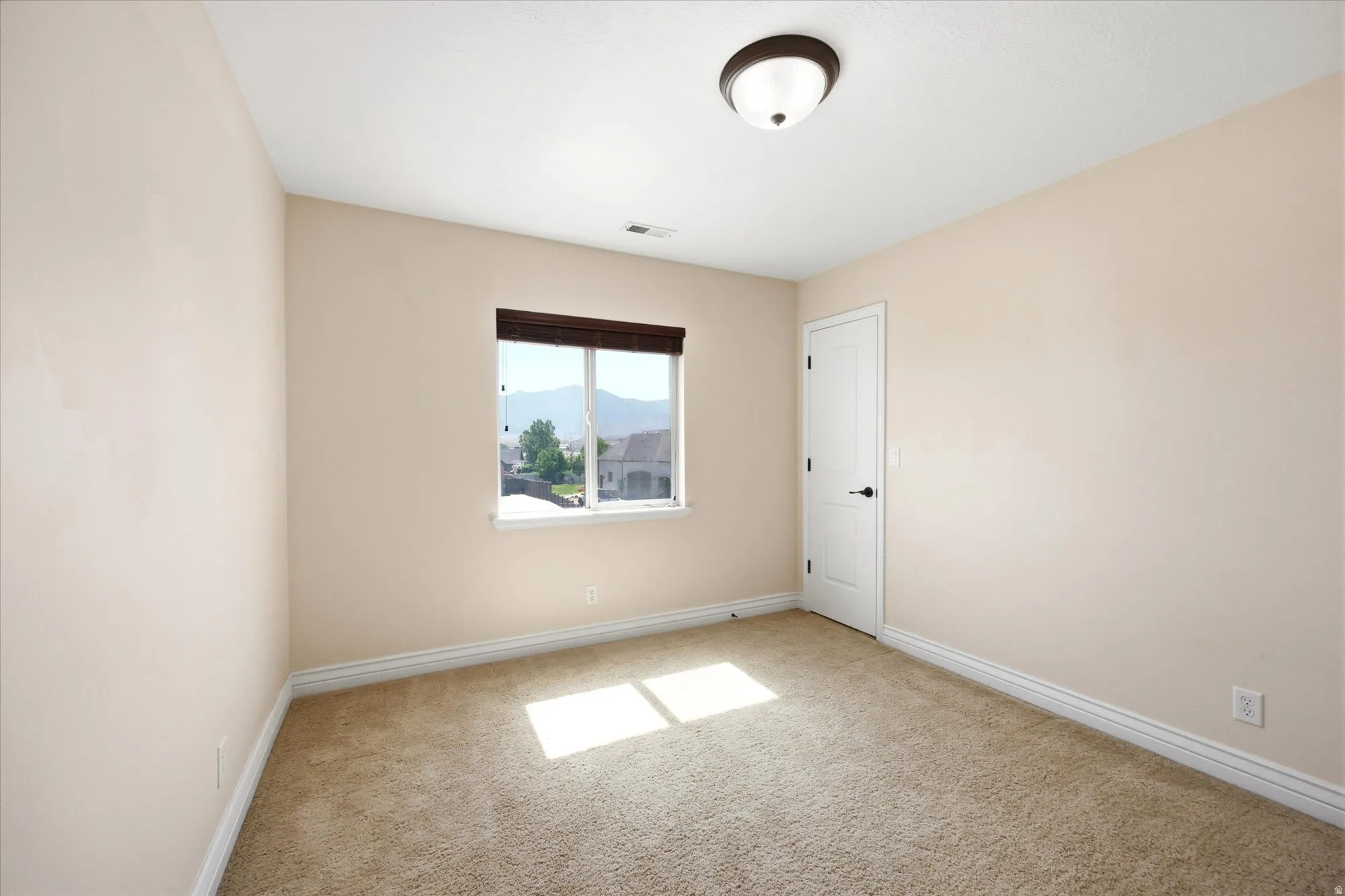 Neutral-toned room featuring light beige walls and a window with dark wood-finish blinds