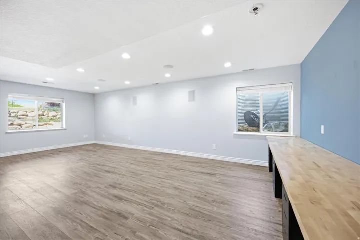 Spacious room featuring recessed lighting, wood-finish flooring, and a built-in wood countertop with storage cabinetry